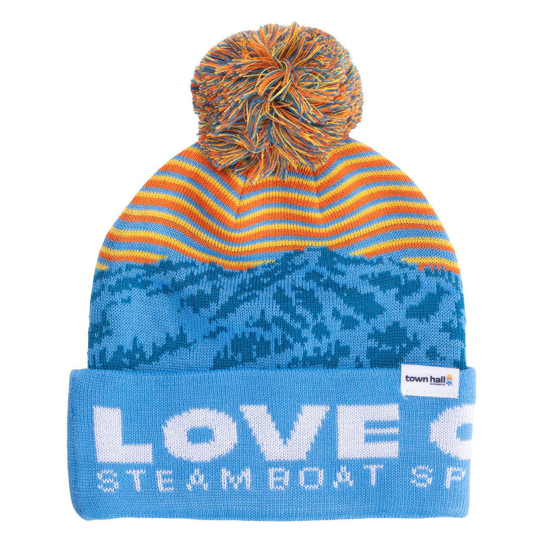 Front view of Town Hall Kids Love Outside Beanie in blue with mountain pattern, orange and yellow stripes, and pom-pom.